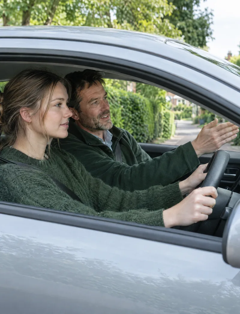 A learner driver at the wheel with her instructor beside her