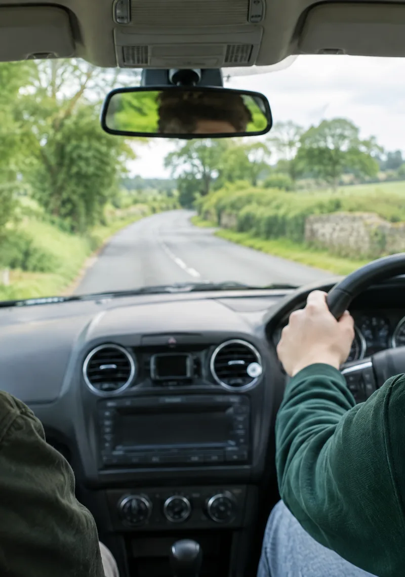 An instructor watching the road from the passenger seat while a learner drives